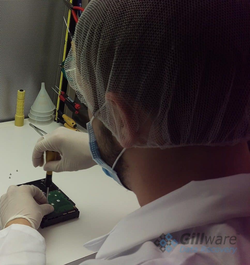 One of our RAID-0 recovery cleanroom engineers disassembling a hard drive for inspection.