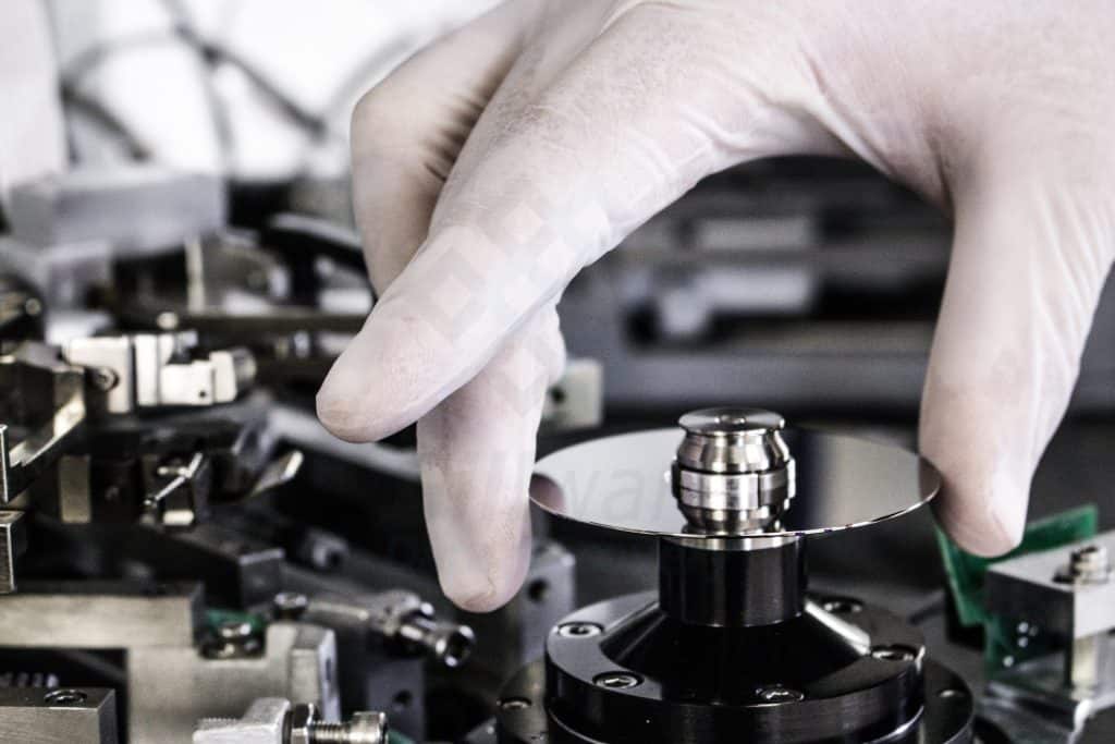 An engineer placing a small glass hard disk platter onto our burnishing machine to clean off microscopic dust and debris