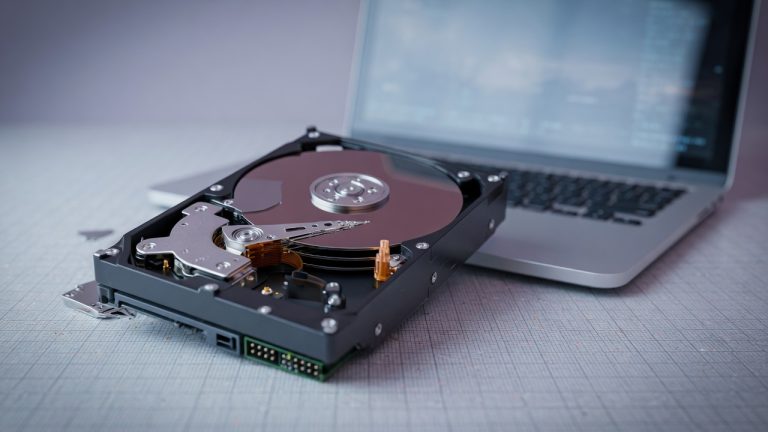 Hard drive freezing a computer: an internal hard drive beside a laptop awaiting data recovery